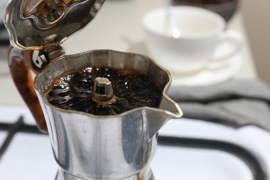 Photo of Brewing aromatic coffee in moka pot on blurred background, closeup. Space for text