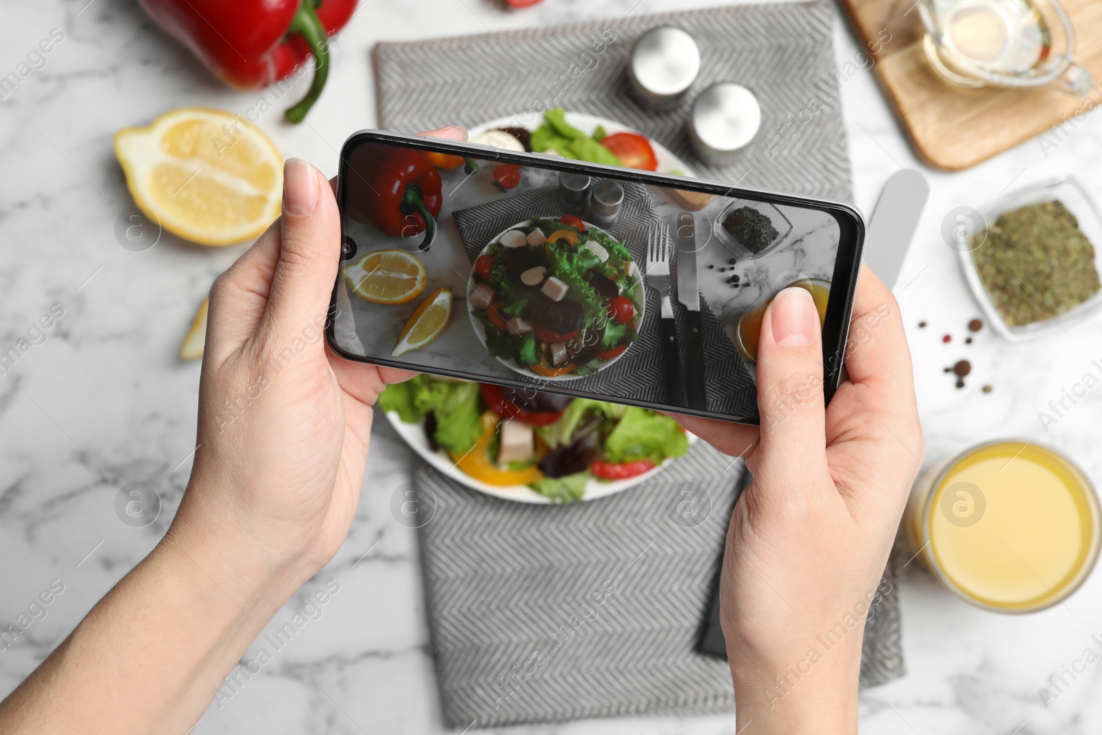 Photo of Blogger taking photo of fresh salad at white marble table, closeup