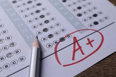 Photo of School grade. Answer sheet with red letter A, plus symbol and pencil on wooden table, closeup