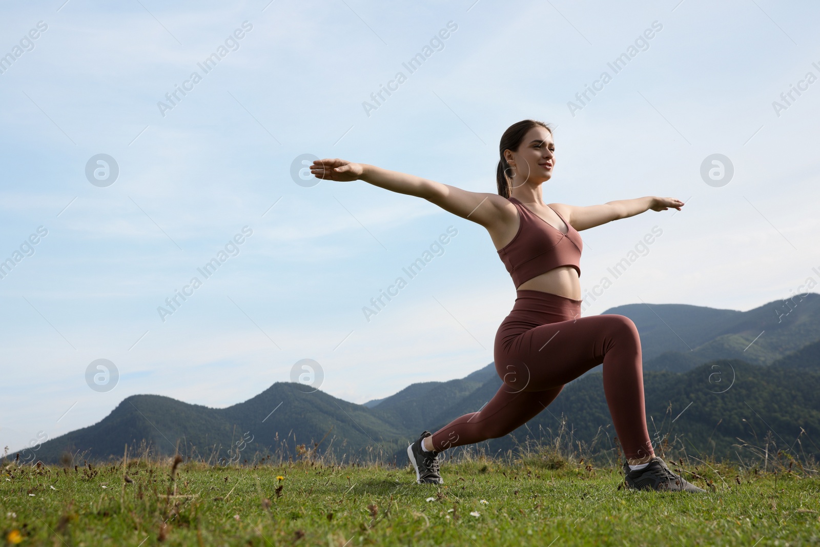 Photo of Young woman doing morning exercise in mountains, space for text