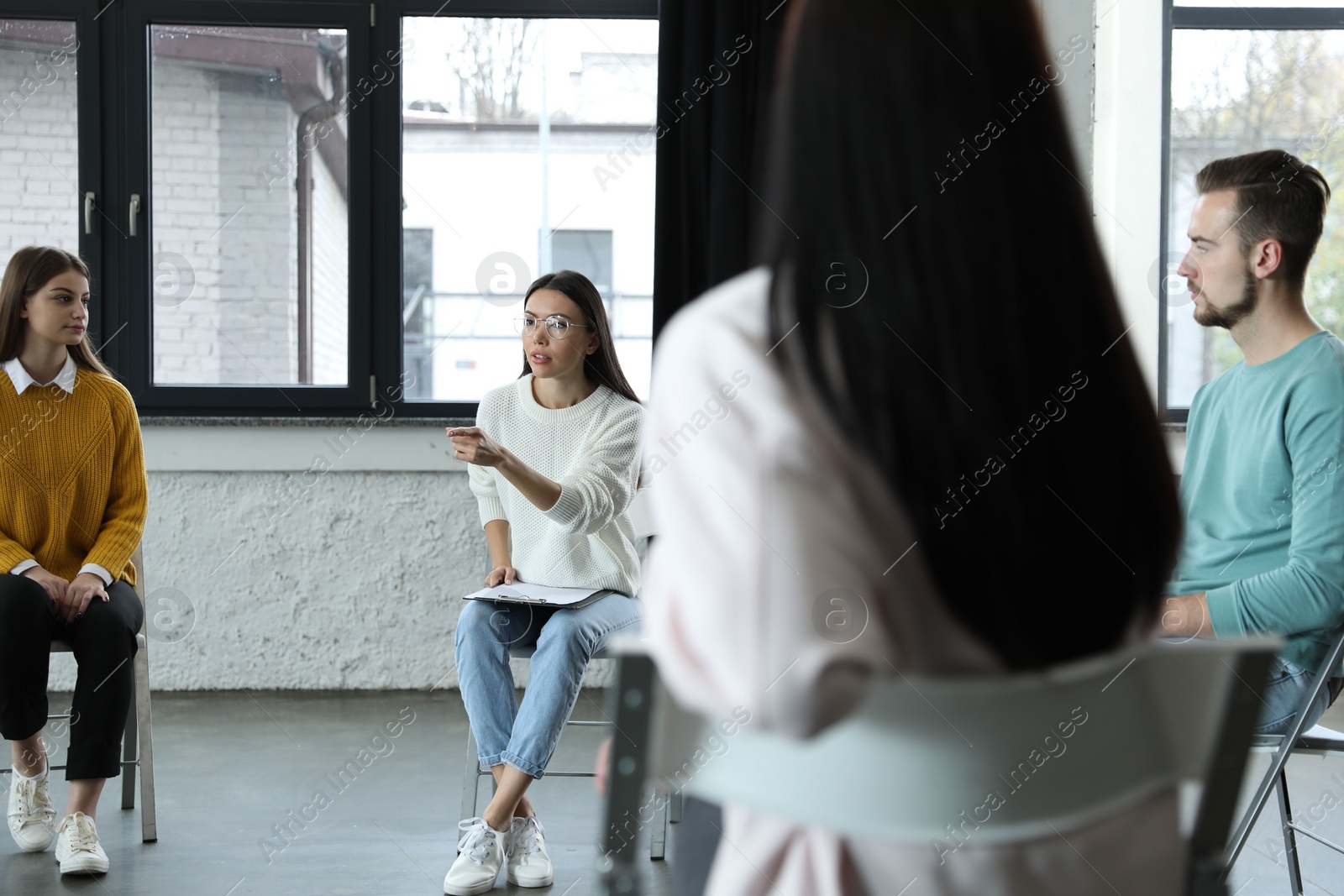 Photo of Psychotherapist working with patients in group therapy session indoors