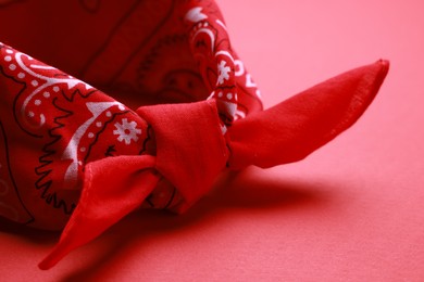 Photo of Tied bandana with paisley pattern on red background, closeup