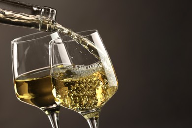 Photo of Pouring tasty aromatic wine in glass on gray background, closeup. Space for text