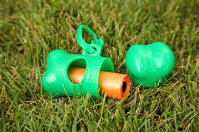 Holder with dog waste bags in green grass outdoors