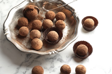 Plate and tasty chocolate truffles on marble background