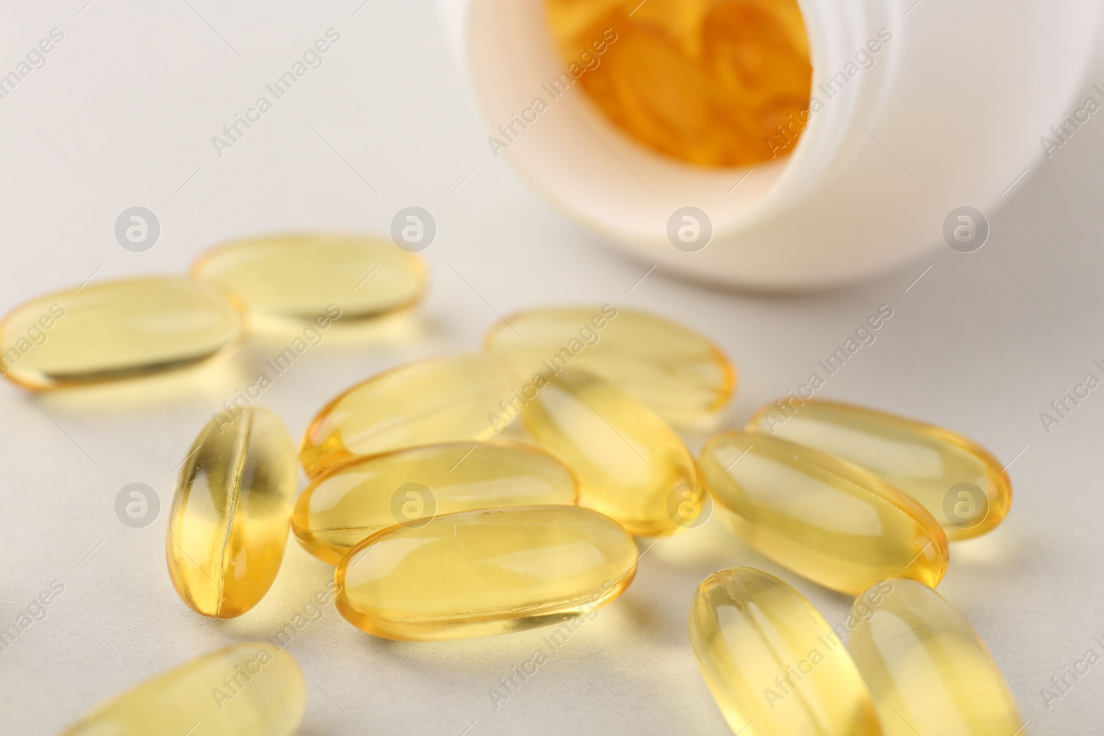 Photo of Vitamin capsules and bottle on light grey background, closeup