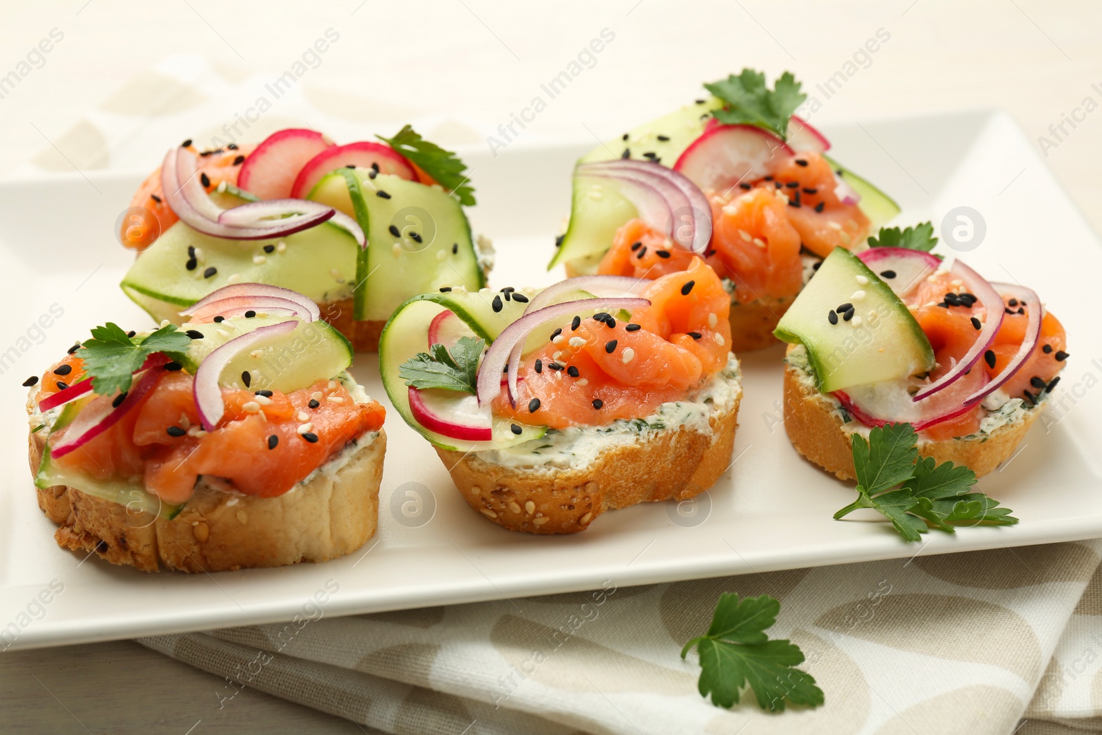 Photo of Tasty canapes with salmon served on white wooden table