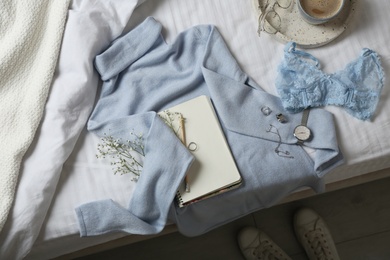 Flat lay composition with soft cashmere sweater on bed at home