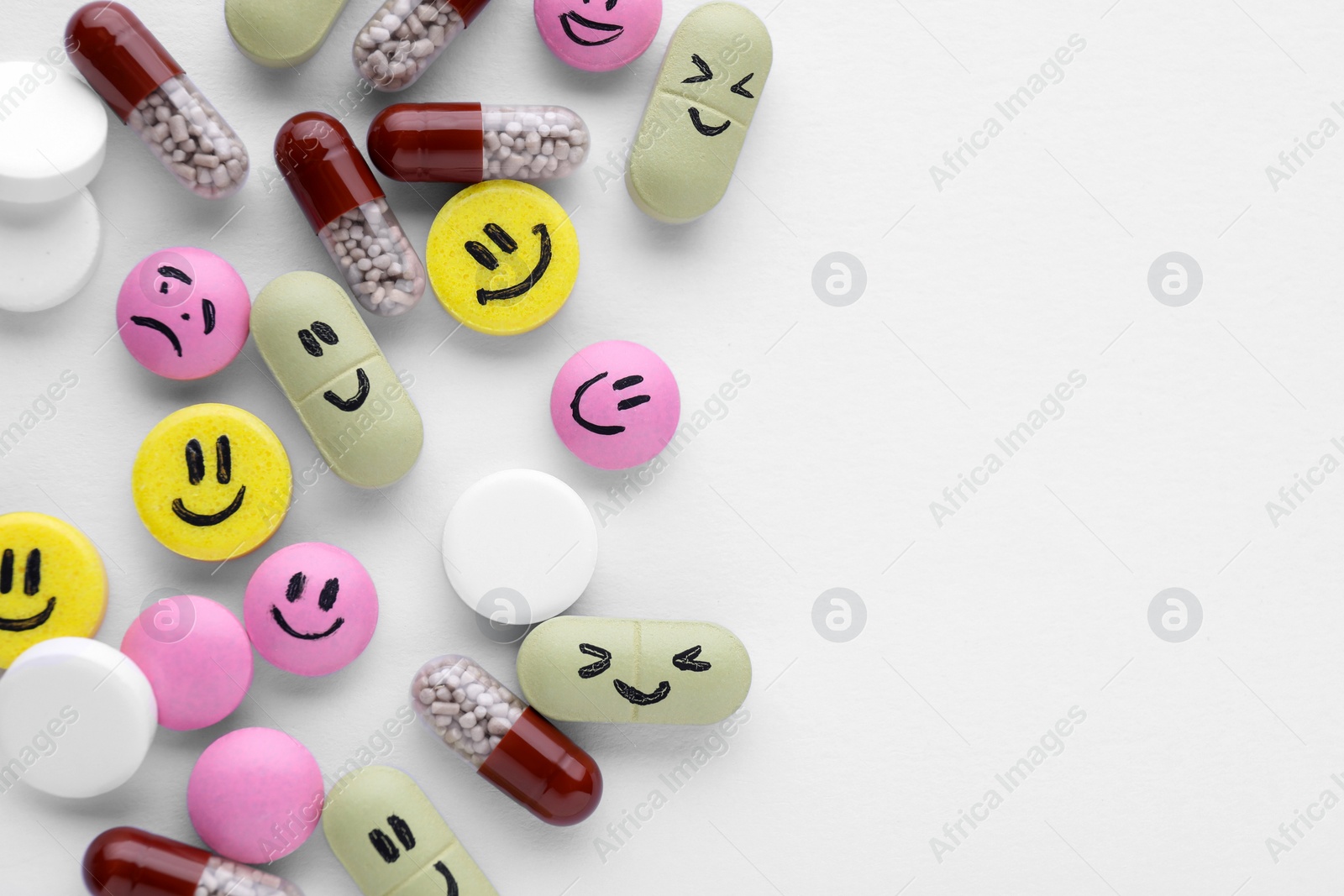 Photo of Antidepressant pills with emotional faces on white background, top view