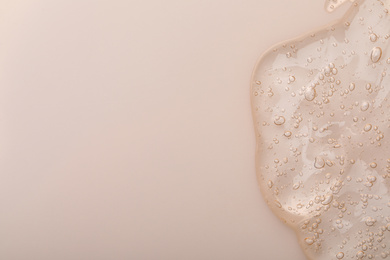 Photo of Pure transparent cosmetic gel on beige background, top view
