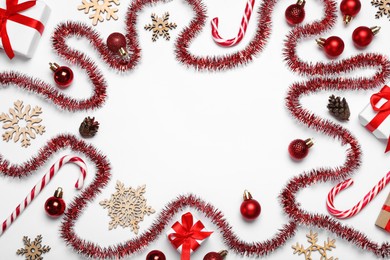 Photo of Frame of red tinsel and Christmas decor on white background, flat lay. Space for text