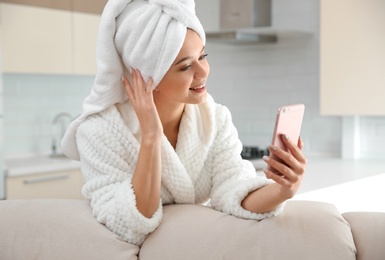 Photo of Beautiful woman with hair wrapped in towel taking selfie at home