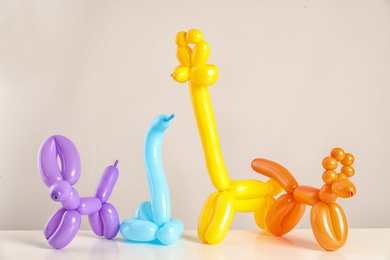 Photo of Animal figures made of modelling balloons on table against color background