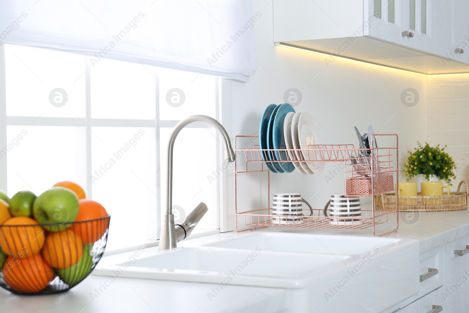 Photo of Clean dishes on drying rack in modern kitchen interior