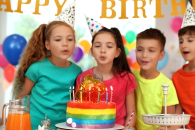 Photo of Children near cake with candles at birthday party indoors