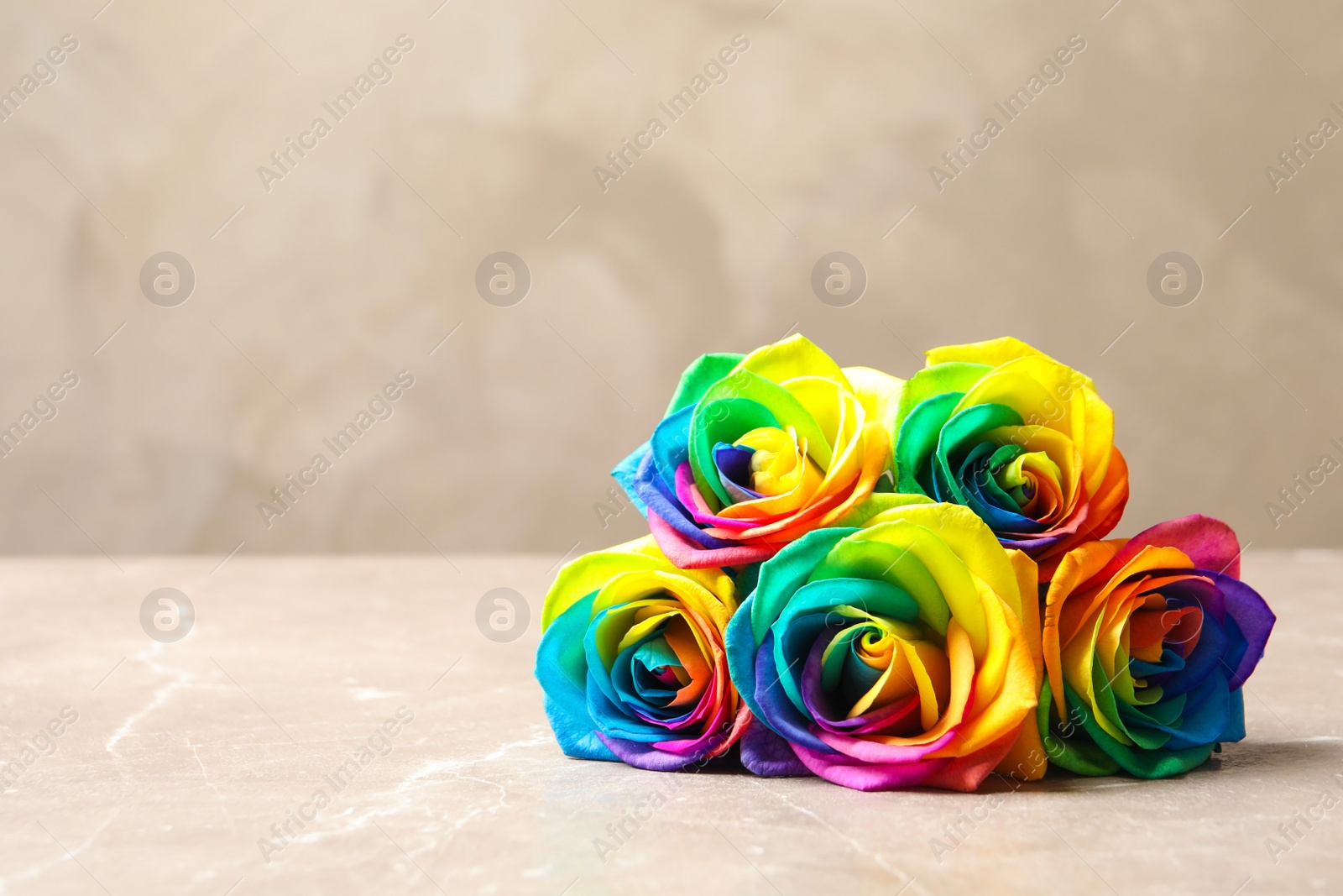 Photo of Amazing rainbow rose flowers on table