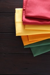 Different colorful napkins on wooden table, space for text