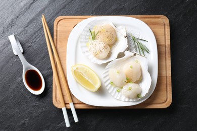 Photo of Raw scallops with green onion, rosemary, lemon and soy sauce on dark textured table, flat lay