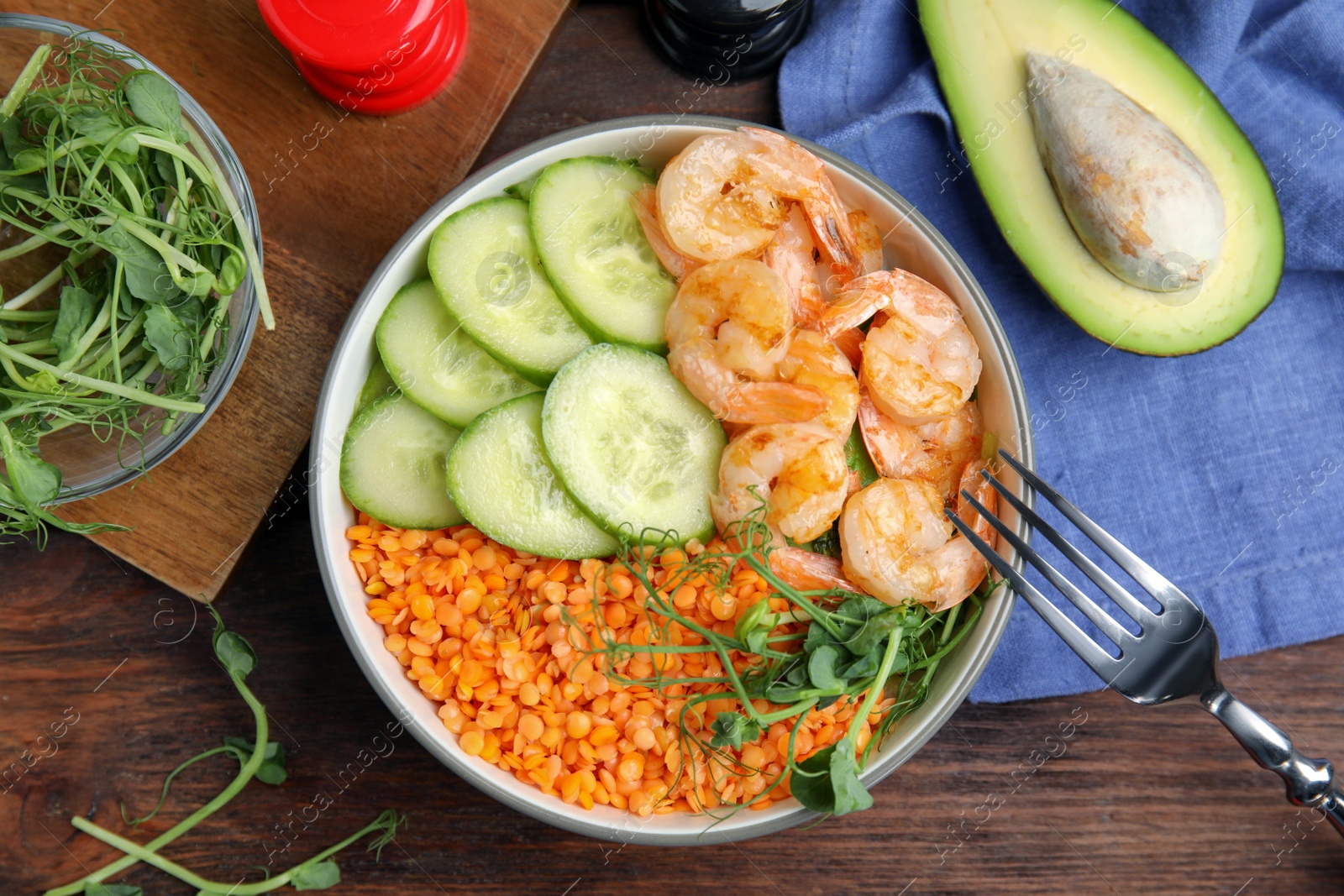 Photo of Delicious lentil bowl with shrimps and cucumber on wooden table, flat lay