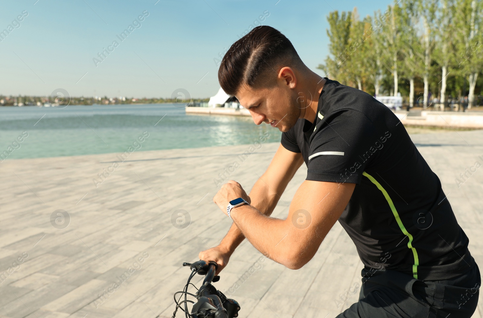 Photo of Man checking modern smart watch during training near river