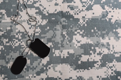 Photo of Military ID tags on camouflage background, top view. Space for text