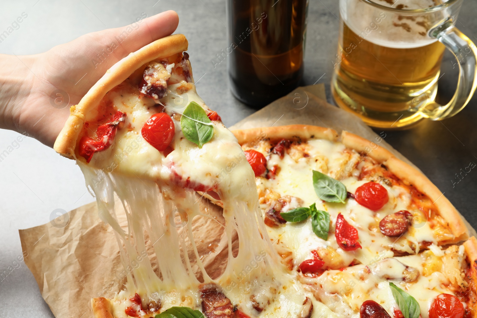 Photo of Woman holding slice of delicious hot pizza over table, closeup