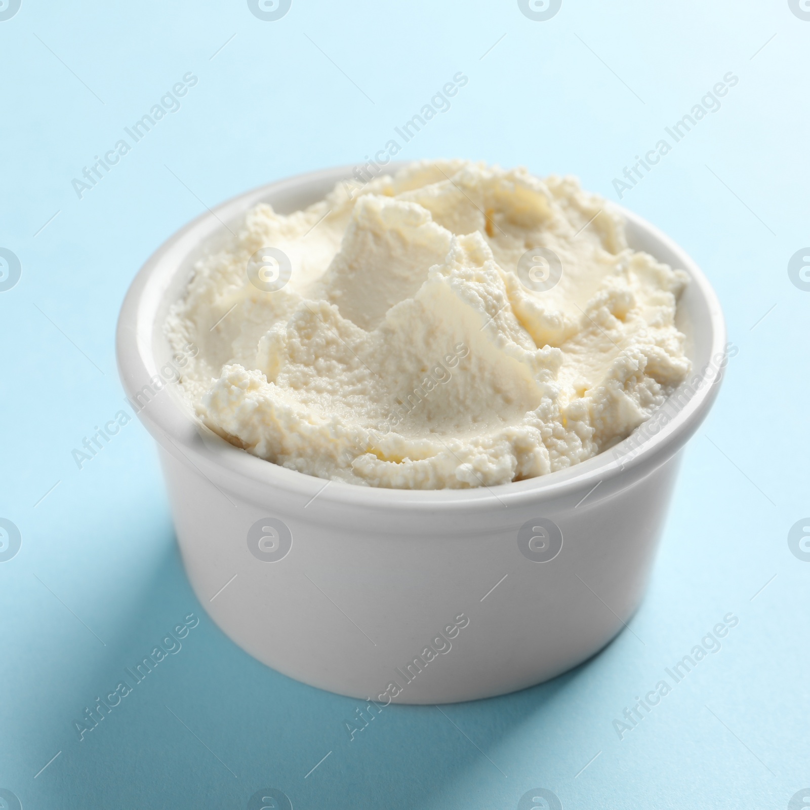 Photo of Bowl of tasty cream cheese on color background