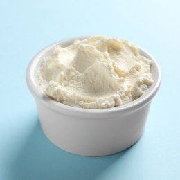 Bowl of tasty cream cheese on color background