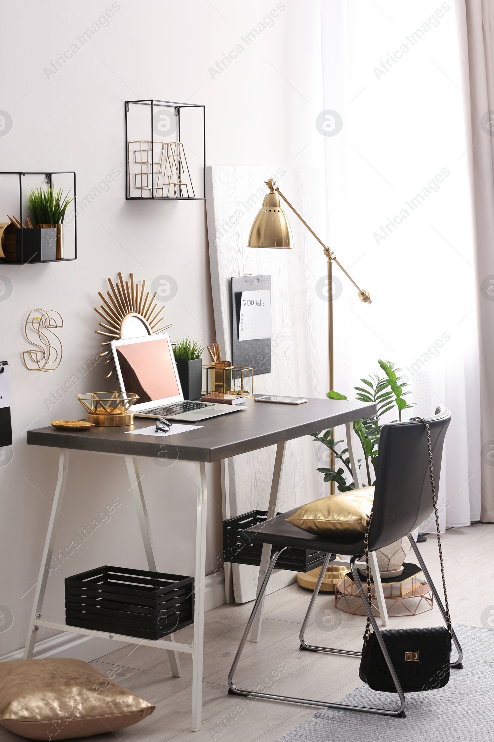 Photo of Modern workplace with laptop and golden decor on desk near wall. Stylish interior design