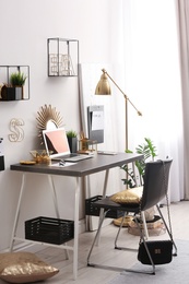 Photo of Modern workplace with laptop and golden decor on desk near wall. Stylish interior design