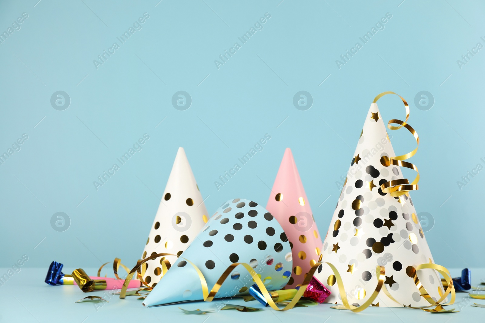 Photo of Colorful party hats and festive items on light blue background. Space for text