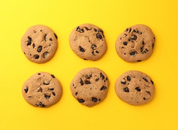 Photo of Delicious chocolate chip cookies on yellow background, flat lay