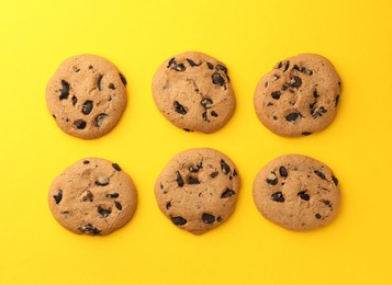 Delicious chocolate chip cookies on yellow background, flat lay