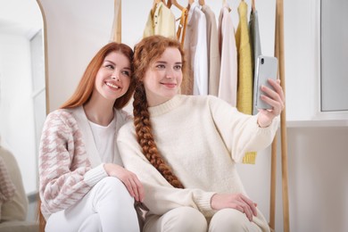 Beautiful young sisters taking selfie in dressing room