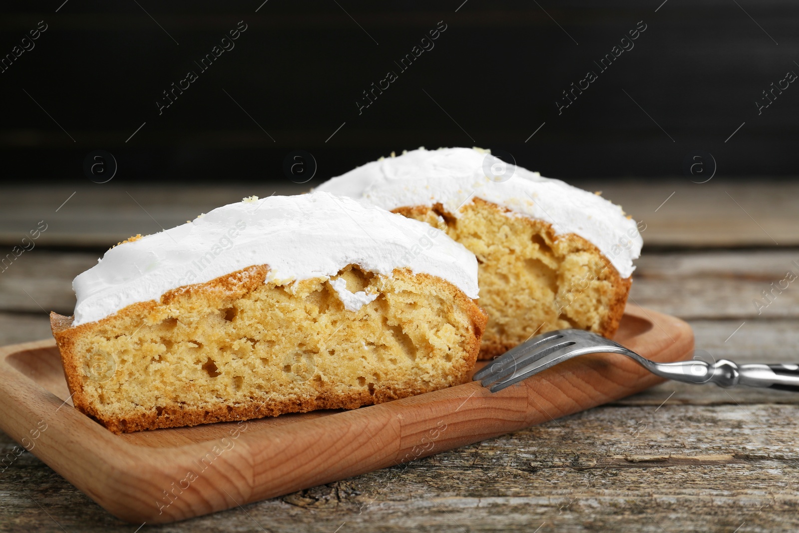 Photo of Pieces of homemade yogurt cake with cream on wooden table, closeup