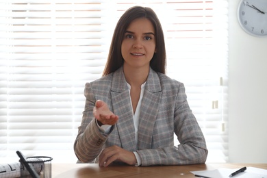 Young woman talking to her coworkers through video conference in office, view from webcam