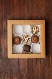 Partially empty box of chocolate candies on wooden table, top view