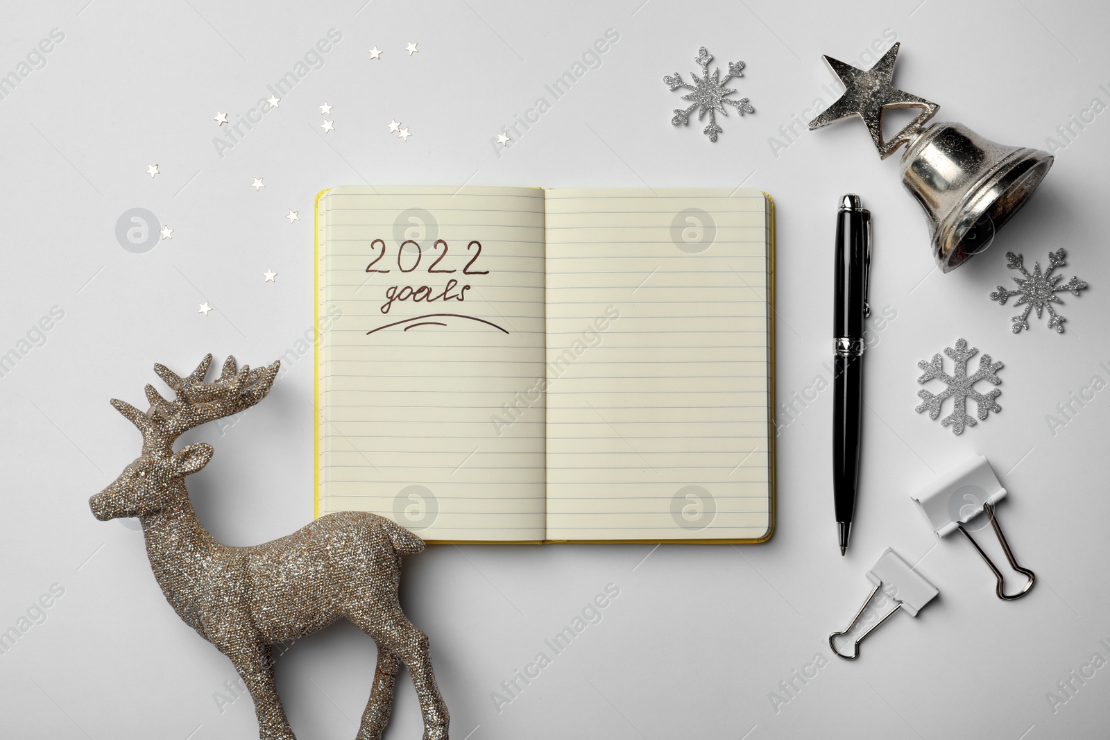 Photo of Inscription 2022 Goals written in planner and Christmas decor on white background, flat lay. New Year aims