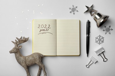 Inscription 2022 Goals written in planner and Christmas decor on white background, flat lay. New Year aims