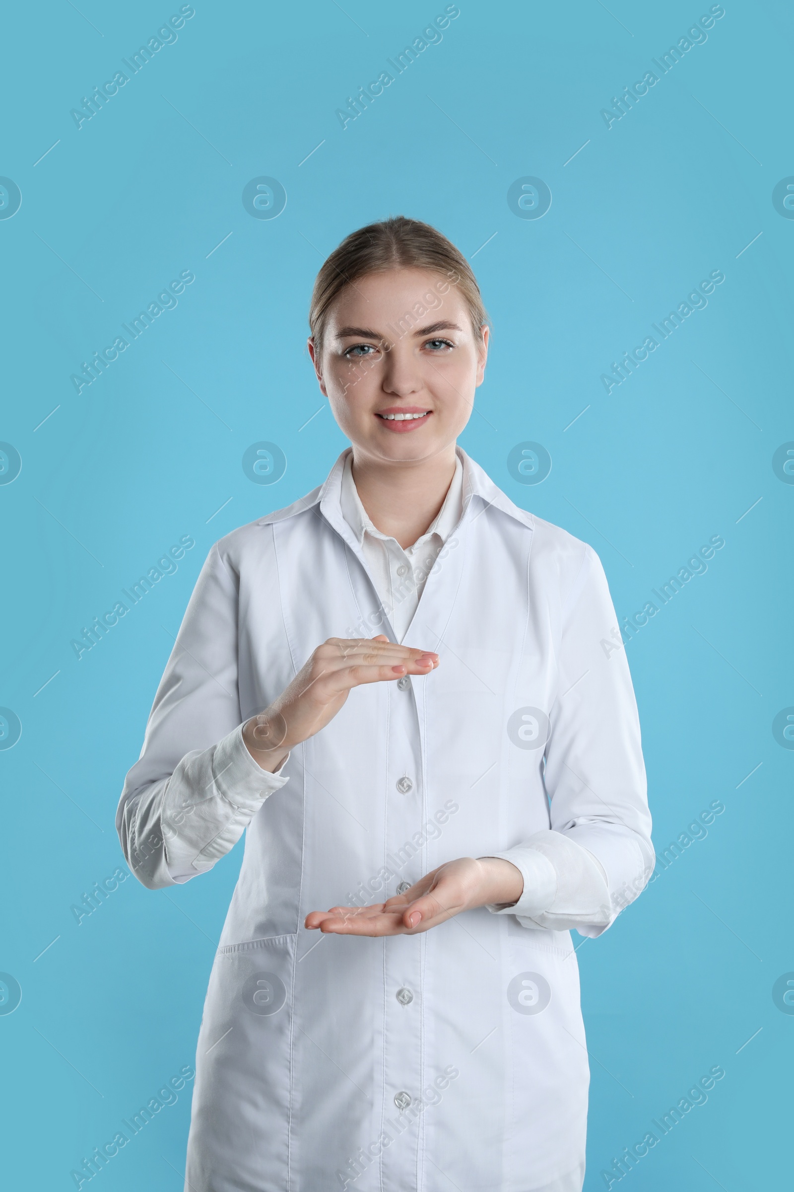 Photo of Dental assistant holding something on light blue background