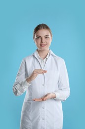 Photo of Dental assistant holding something on light blue background