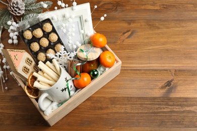 Photo of Crate with gift set and Christmas decor on wooden table, above view. Space for text