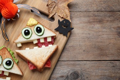 Photo of Cute monster sandwiches served on wooden table, flat lay with space for text. Halloween party food