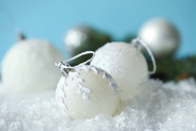 Beautiful Christmas balls on snow against light blue background