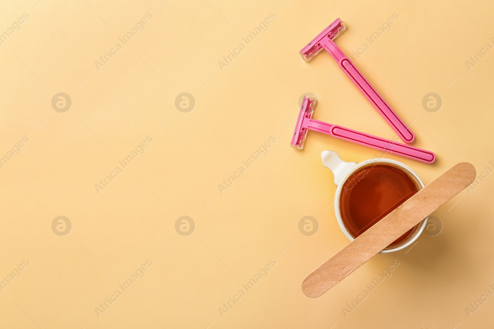 Photo of Sugaring paste and razors on color background, flat lay