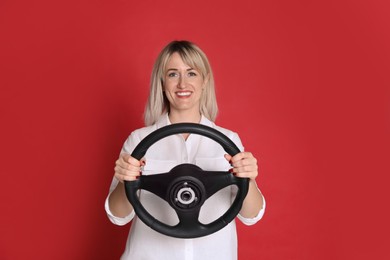 Photo of Happy woman with steering wheel on red background