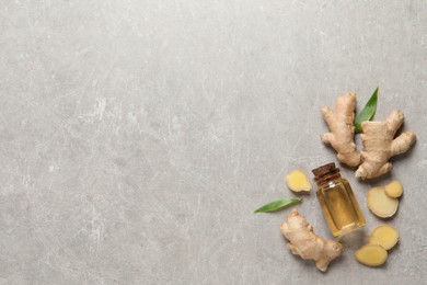 Photo of Glass bottle of essential oil and ginger root on light grey table, flat lay. Space for text