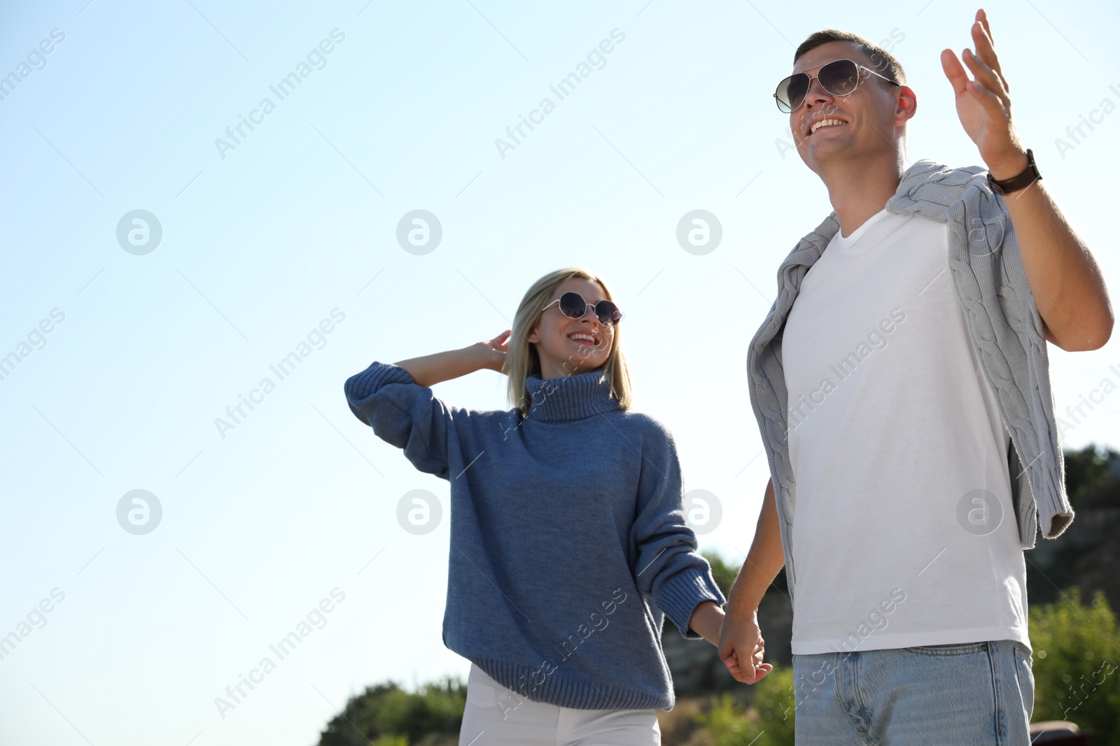Photo of Happy couple in stylish sweaters outdoors on sunny day
