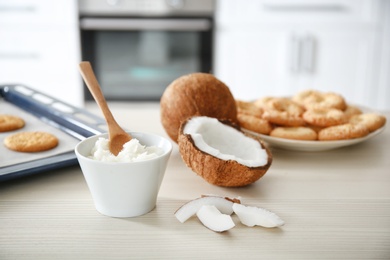 Photo of Bowl with coconut oil and nut pieces on wooden table