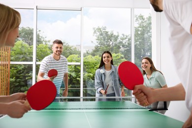 Happy friends playing ping pong together indoors